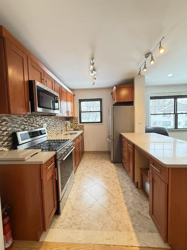 kitchen with tasteful backsplash, sink, light tile patterned floors, kitchen peninsula, and stainless steel appliances