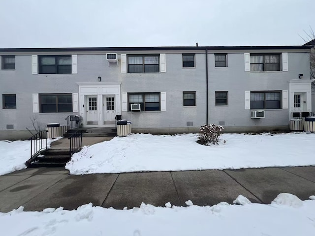 snow covered back of property featuring a wall mounted AC, central AC unit, and cooling unit