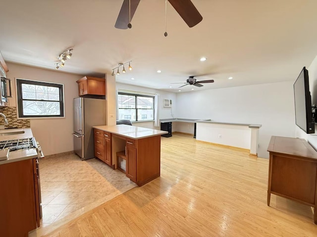 kitchen featuring high quality fridge, a healthy amount of sunlight, sink, and light wood-type flooring