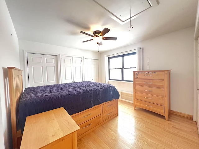 bedroom featuring ceiling fan, light hardwood / wood-style floors, and multiple closets