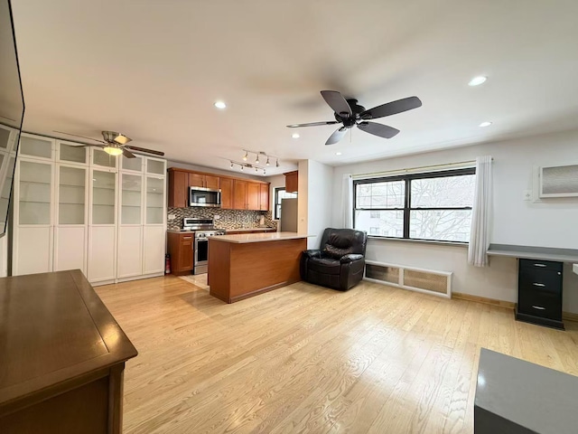 kitchen featuring tasteful backsplash, ceiling fan, kitchen peninsula, stainless steel appliances, and light wood-type flooring