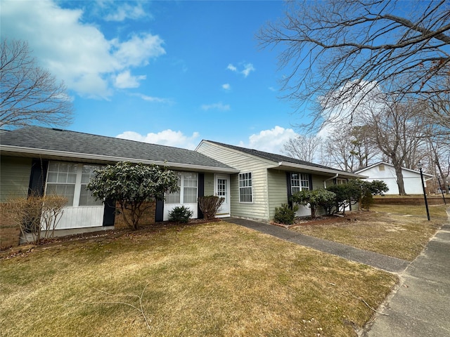 ranch-style home with a shingled roof and a front lawn