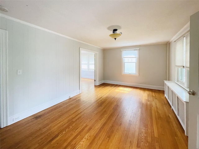 spare room with crown molding and light wood-type flooring