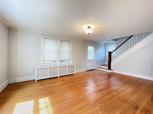 unfurnished living room with radiator heating unit and light hardwood / wood-style floors