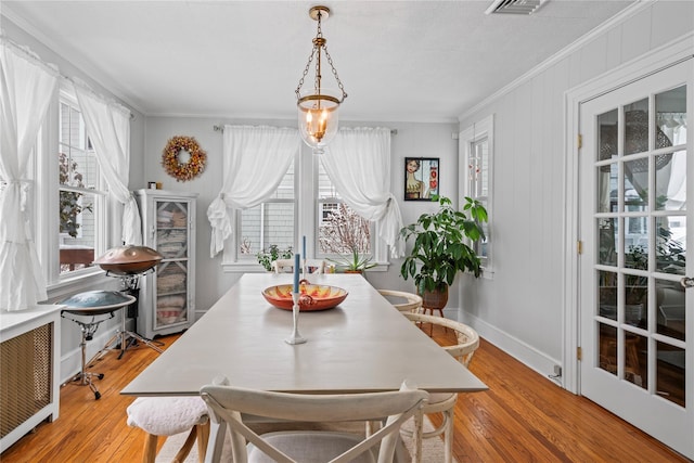 dining room featuring ornamental molding, radiator heating unit, and light hardwood / wood-style floors