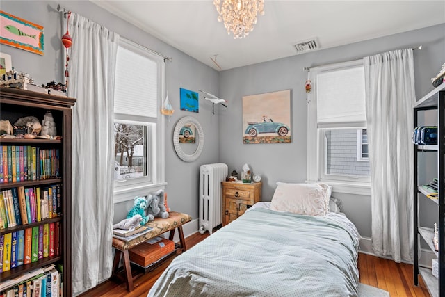 bedroom featuring a notable chandelier, hardwood / wood-style flooring, and radiator heating unit