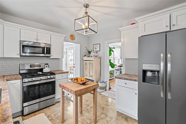 kitchen featuring hanging light fixtures, backsplash, stainless steel appliances, a notable chandelier, and white cabinets