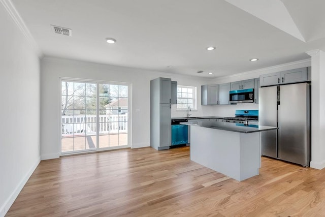 kitchen with light wood finished floors, visible vents, appliances with stainless steel finishes, crown molding, and a sink