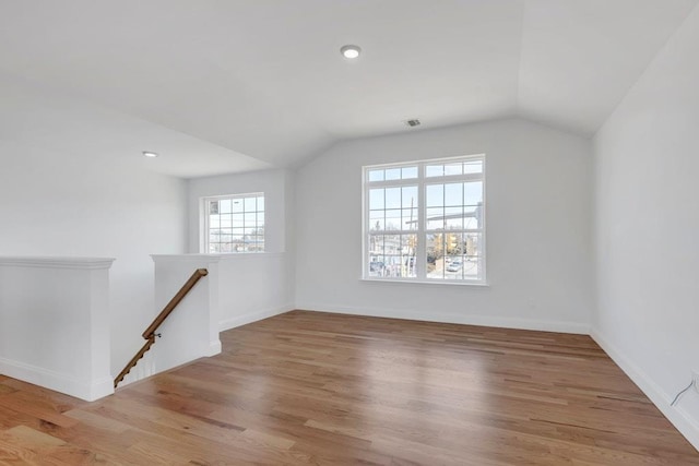 spare room with vaulted ceiling, baseboards, and wood finished floors