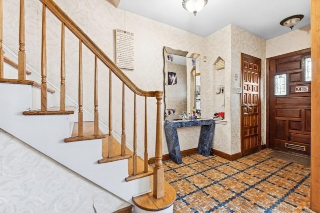 entryway featuring wallpapered walls, baseboards, and stairway