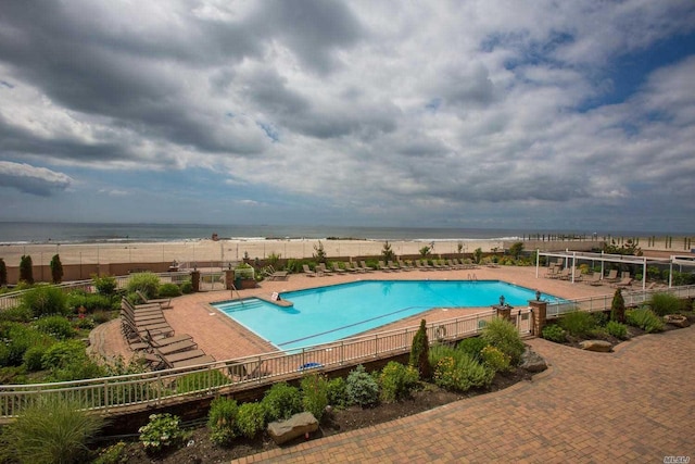 pool featuring a water view, fence, and a patio