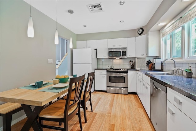 kitchen with dark countertops, visible vents, appliances with stainless steel finishes, and a sink