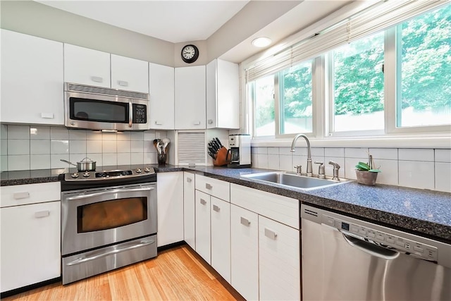 kitchen featuring appliances with stainless steel finishes, backsplash, a sink, and white cabinets