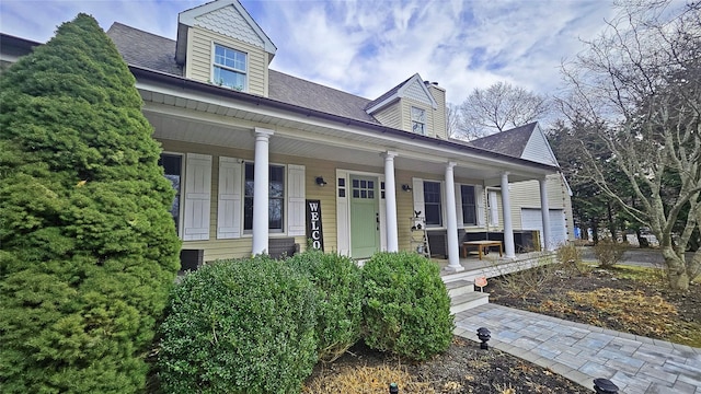 cape cod house with a porch and a shingled roof