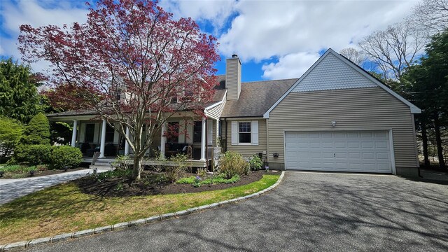 2 Bridle Path, Westhampton Beach, NY 11978 - view of front facade featuring an attached garage, a chimney, covered porch, and driveway