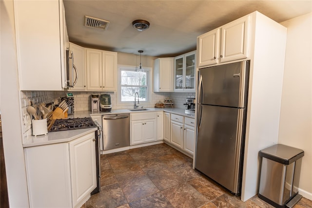 kitchen featuring sink, hanging light fixtures, backsplash, stainless steel appliances, and white cabinets