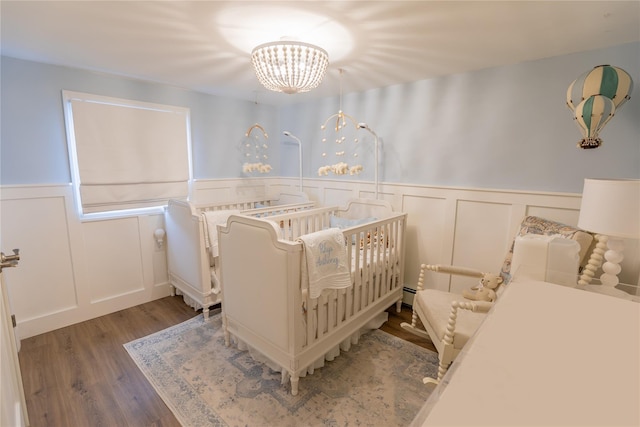 bedroom featuring a notable chandelier, hardwood / wood-style flooring, and baseboard heating