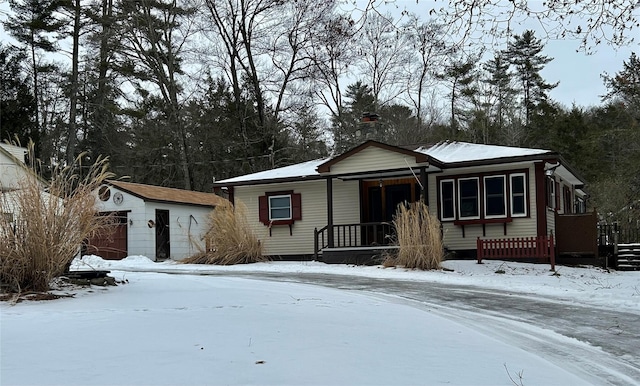 view of front of property with an outdoor structure, covered porch, and a detached garage