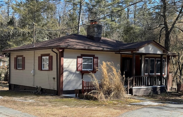 view of front facade with covered porch and a chimney