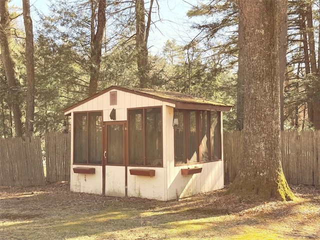 view of outdoor structure featuring a sunroom and fence