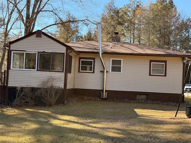 back of property featuring a lawn, roof with shingles, and a chimney