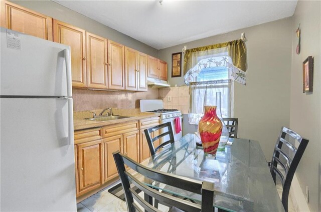 kitchen with tasteful backsplash, white appliances, sink, and light brown cabinets