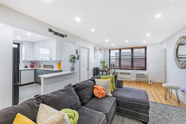 living room with a wall mounted AC, radiator, and light wood-type flooring