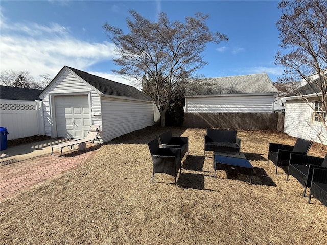 exterior space with a detached garage, fence, an outdoor structure, driveway, and a patio area