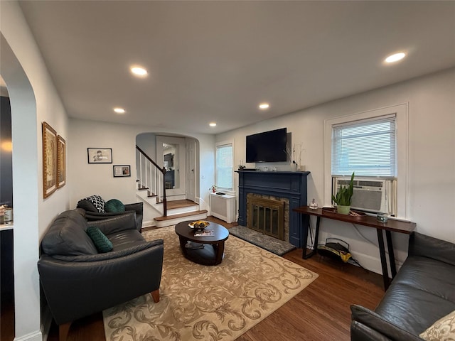 living area featuring stairway, arched walkways, dark wood finished floors, and cooling unit