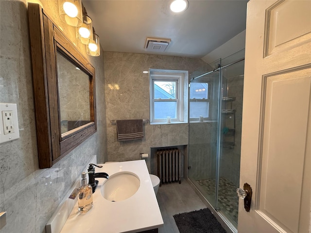 full bathroom featuring tile walls, radiator, visible vents, a stall shower, and vanity