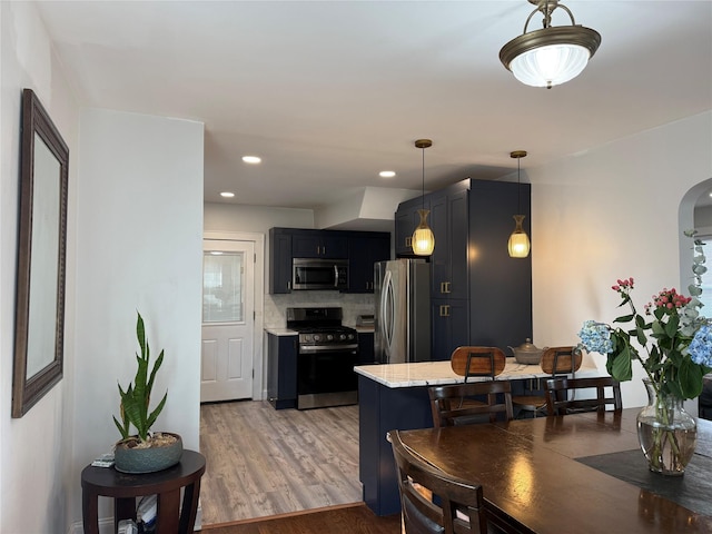 204 N Grove St, Valley Stream, NY 11580 - kitchen featuring stainless steel appliances, arched walkways, light wood-type flooring, light stone countertops, and hanging light fixtures
