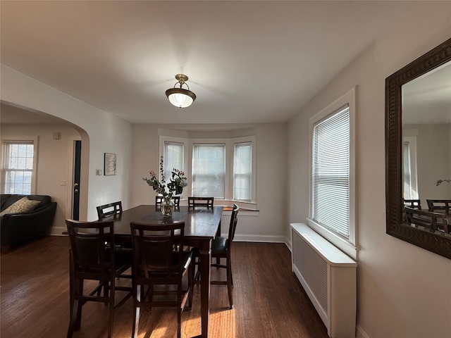 204 N Grove St, Valley Stream, NY 11580 - dining area featuring arched walkways, dark wood-style flooring, baseboards, and radiator heating unit
