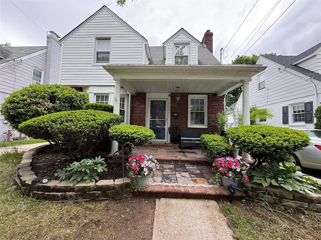 204 N Grove St, Valley Stream, NY 11580 - view of front facade featuring a porch, brick siding, and a chimney