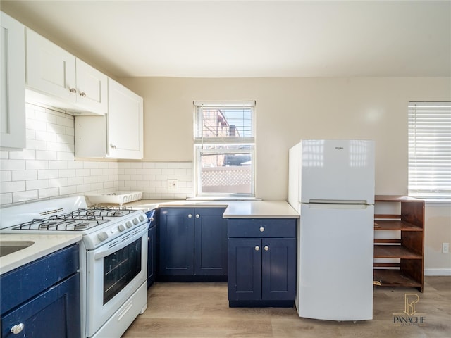 kitchen with white appliances, light wood-type flooring, white cabinets, and blue cabinets