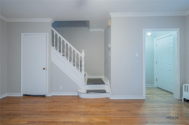 staircase with wood-type flooring and ornamental molding