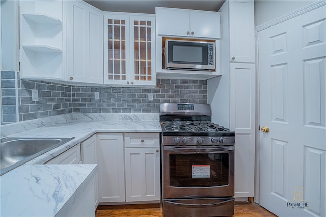 kitchen featuring sink, white cabinetry, tasteful backsplash, light stone counters, and appliances with stainless steel finishes