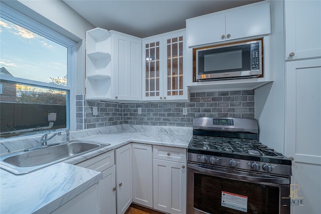 kitchen featuring stainless steel appliances, sink, decorative backsplash, and white cabinets