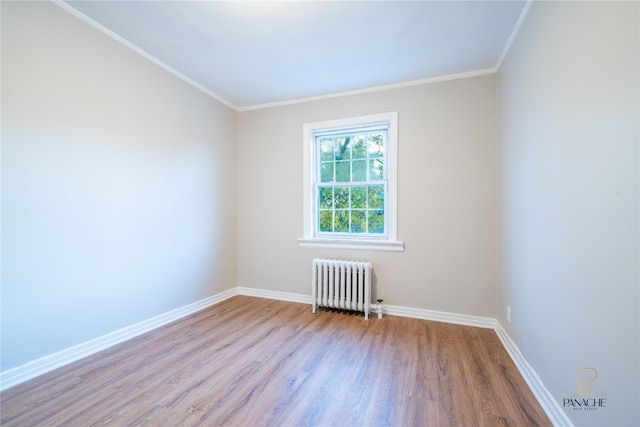 spare room featuring crown molding, radiator heating unit, and light hardwood / wood-style flooring