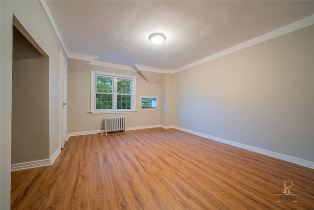 empty room with radiator, crown molding, and light hardwood / wood-style floors