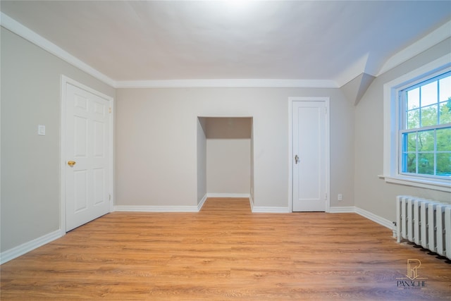 unfurnished room featuring crown molding, radiator heating unit, and light wood-type flooring