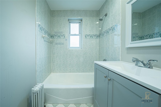 bathroom featuring tiled shower / bath, vanity, and radiator