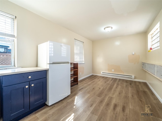 kitchen featuring white refrigerator, wood-type flooring, and a baseboard heating unit