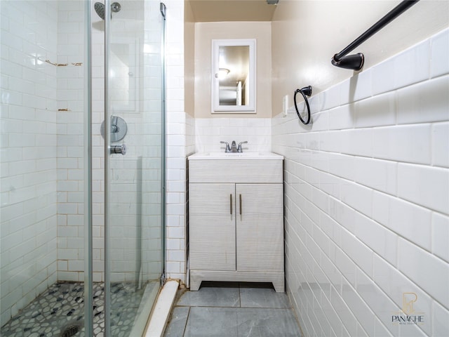 bathroom featuring tile walls, vanity, tile patterned floors, and a shower with door