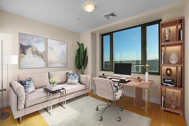 home office with light wood-type flooring and visible vents