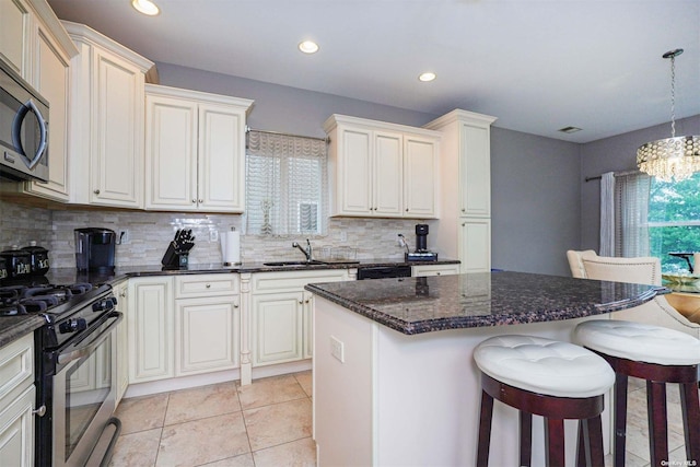 kitchen with sink, appliances with stainless steel finishes, a kitchen island, pendant lighting, and a healthy amount of sunlight