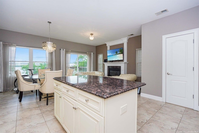 kitchen with dark stone countertops, hanging light fixtures, and a kitchen island