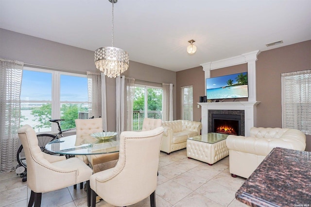 dining room with a fireplace, light tile patterned floors, and a notable chandelier