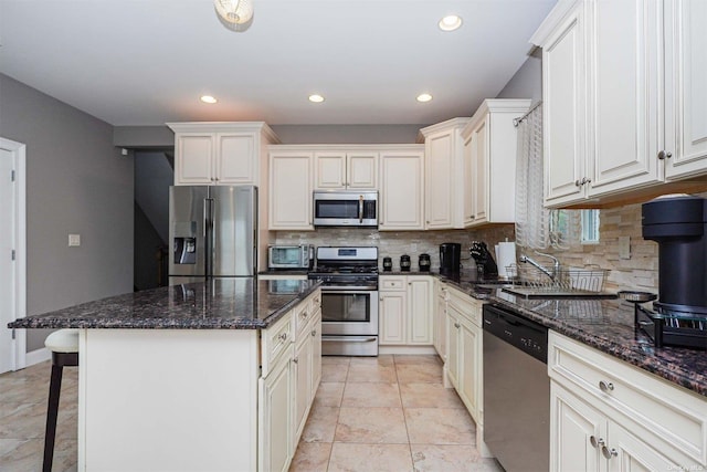 kitchen with stainless steel appliances, a kitchen island, a breakfast bar area, and dark stone countertops