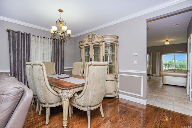 dining area with wood-type flooring, ornamental molding, and an inviting chandelier