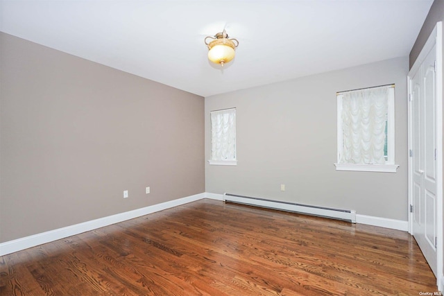 unfurnished room featuring dark hardwood / wood-style flooring and a baseboard heating unit